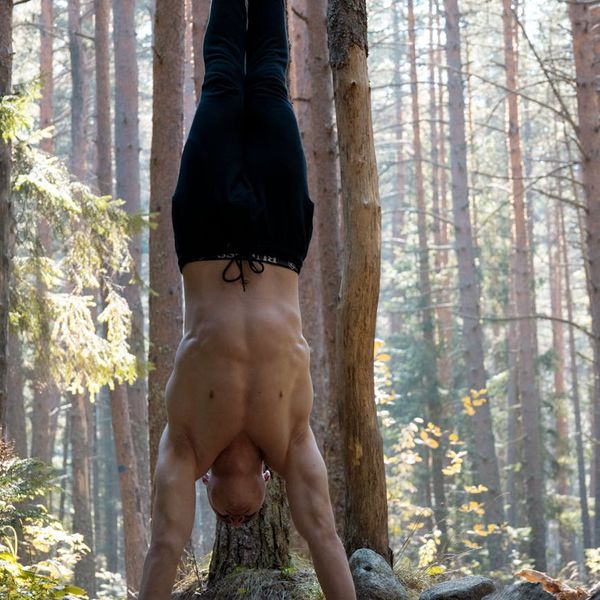A man in a focused state during a stretching exercise, sunlight streaming in.